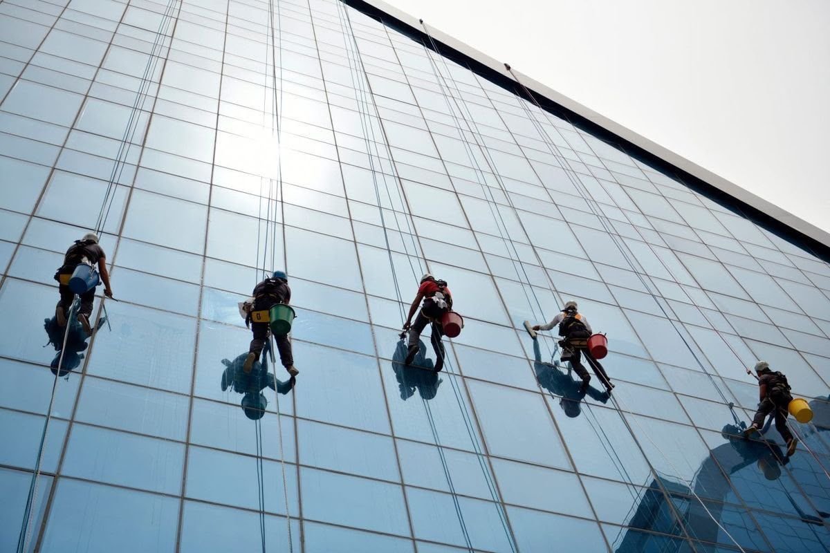 Five rope access technicians cleaning a glass curtain wall